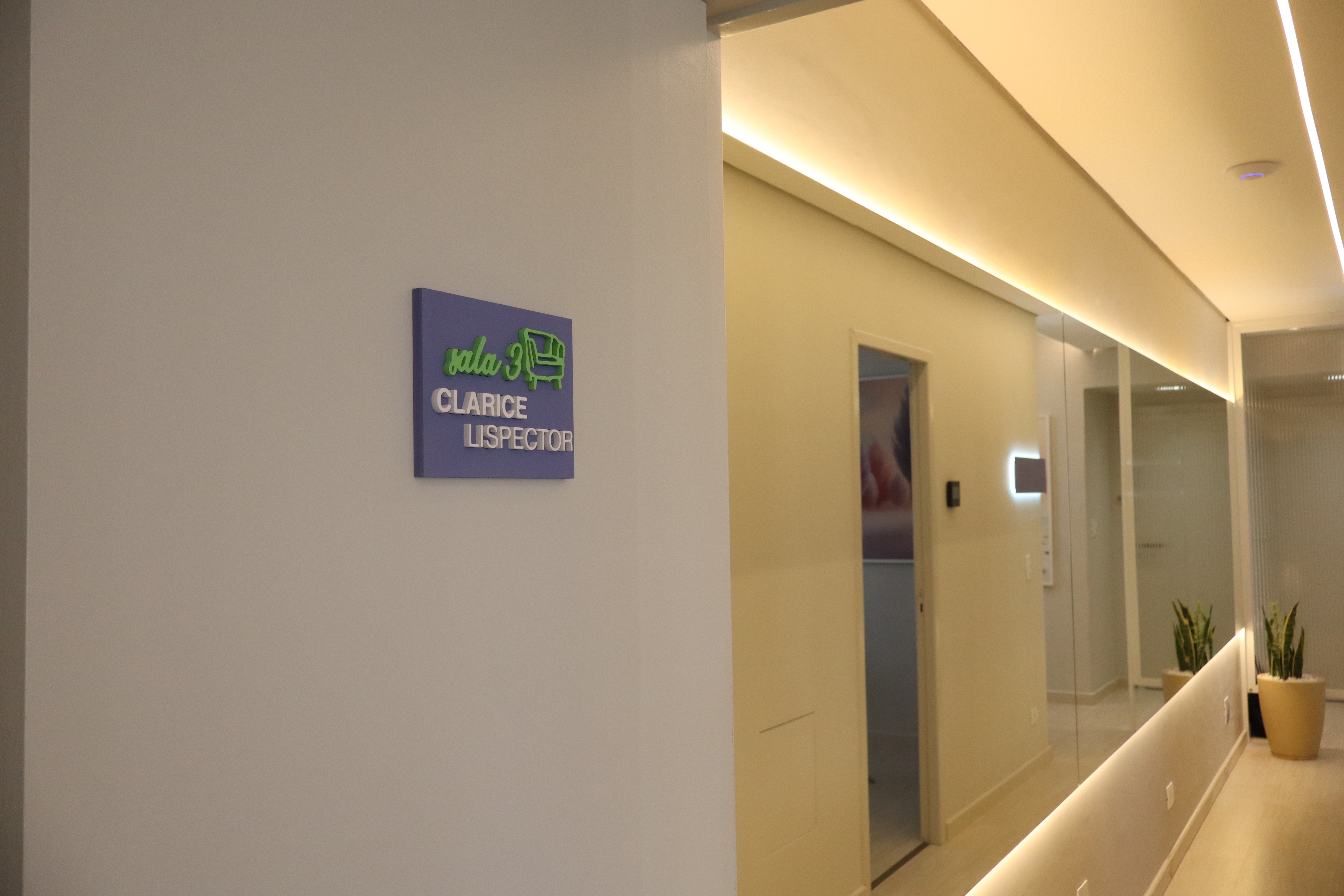 Corredor moderno com iluminação suave e placa da sala
